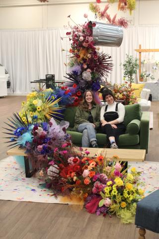 Painted rainbow installation in colourful lounge with two Bespoke Blossoms team members